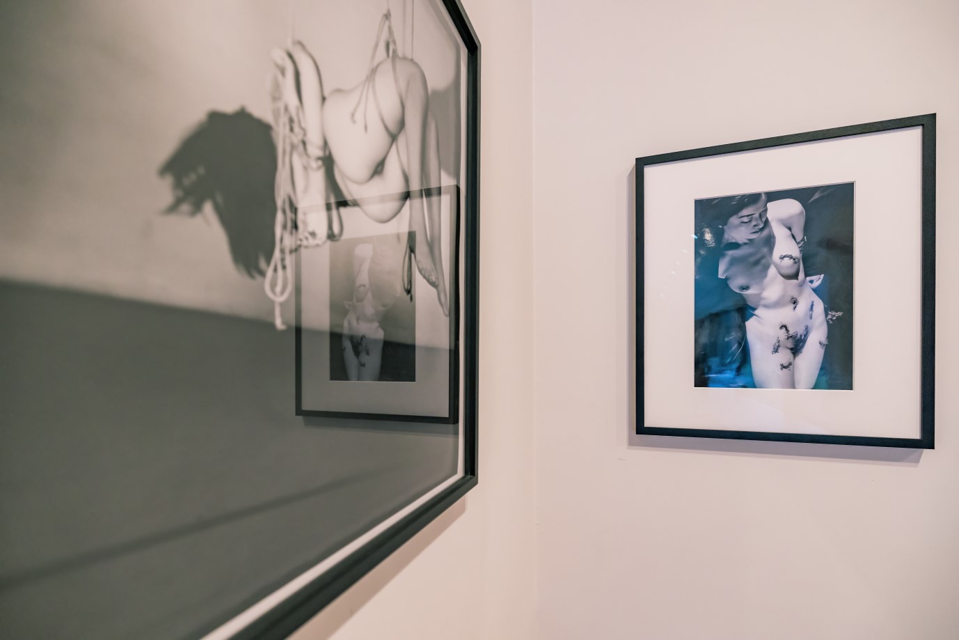 Twee ingekaderde foto's van naakte lichamen aan de wand