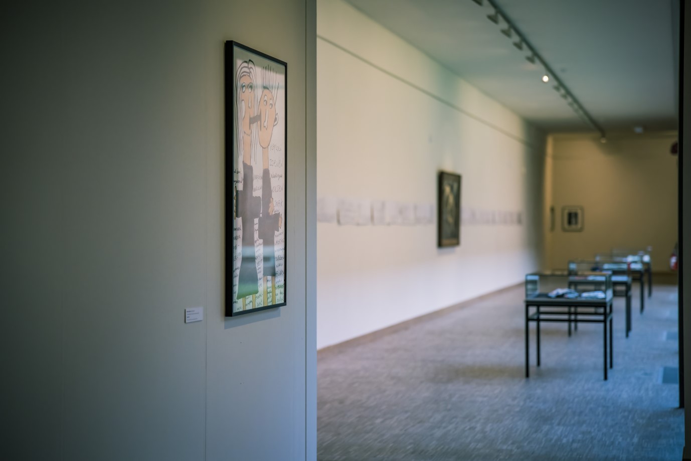 Tekening van twee figuren aan de wand met zicht op tentoonstellingsruimte