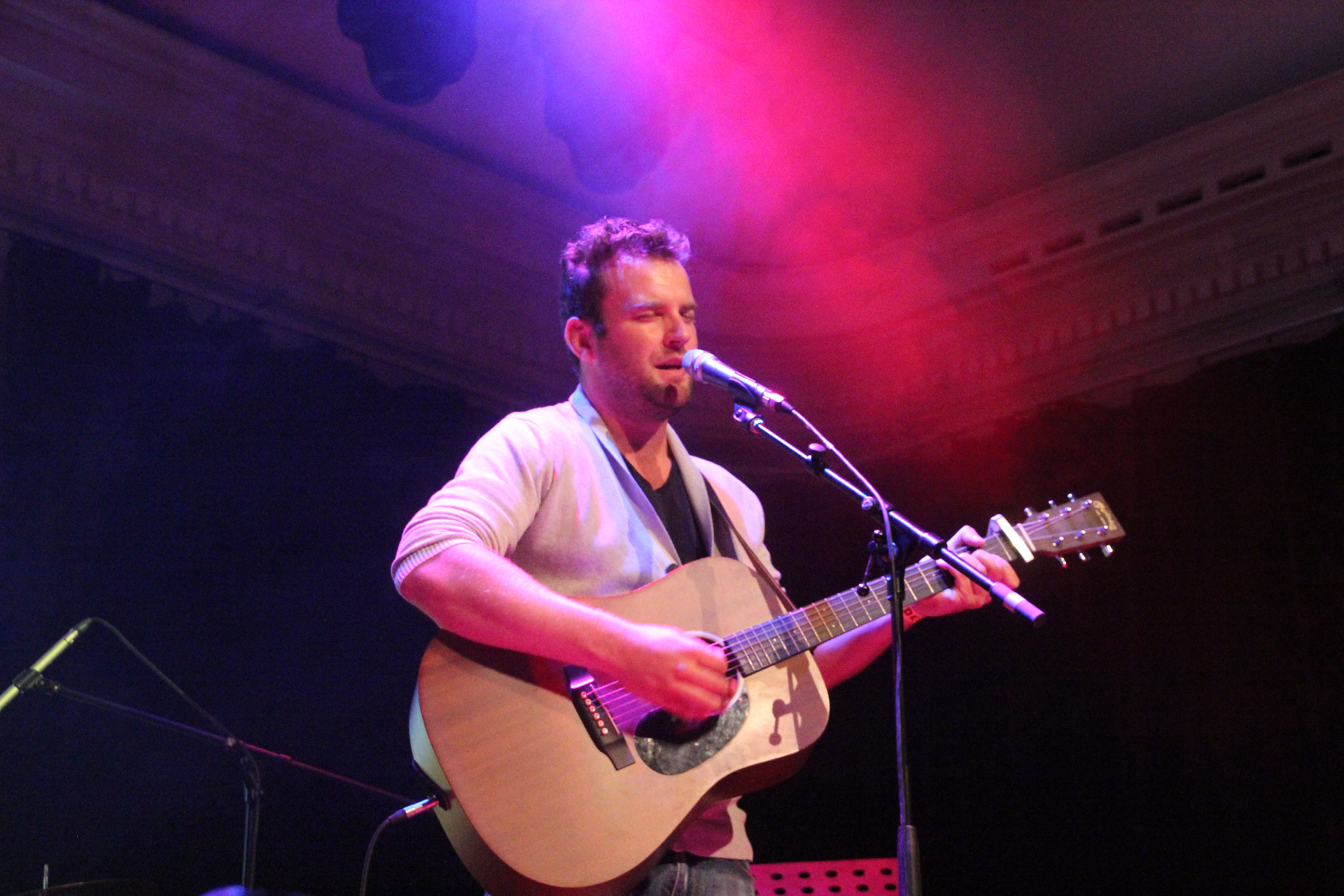 Singer-songwriter met akoestische gitaar in rood licht