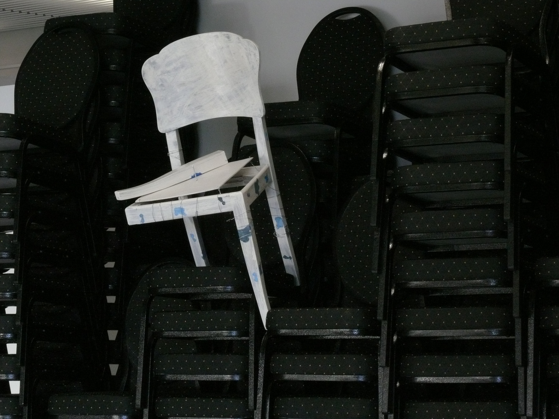 Witte beschilderde stoel op een stapel zwarte stoelen