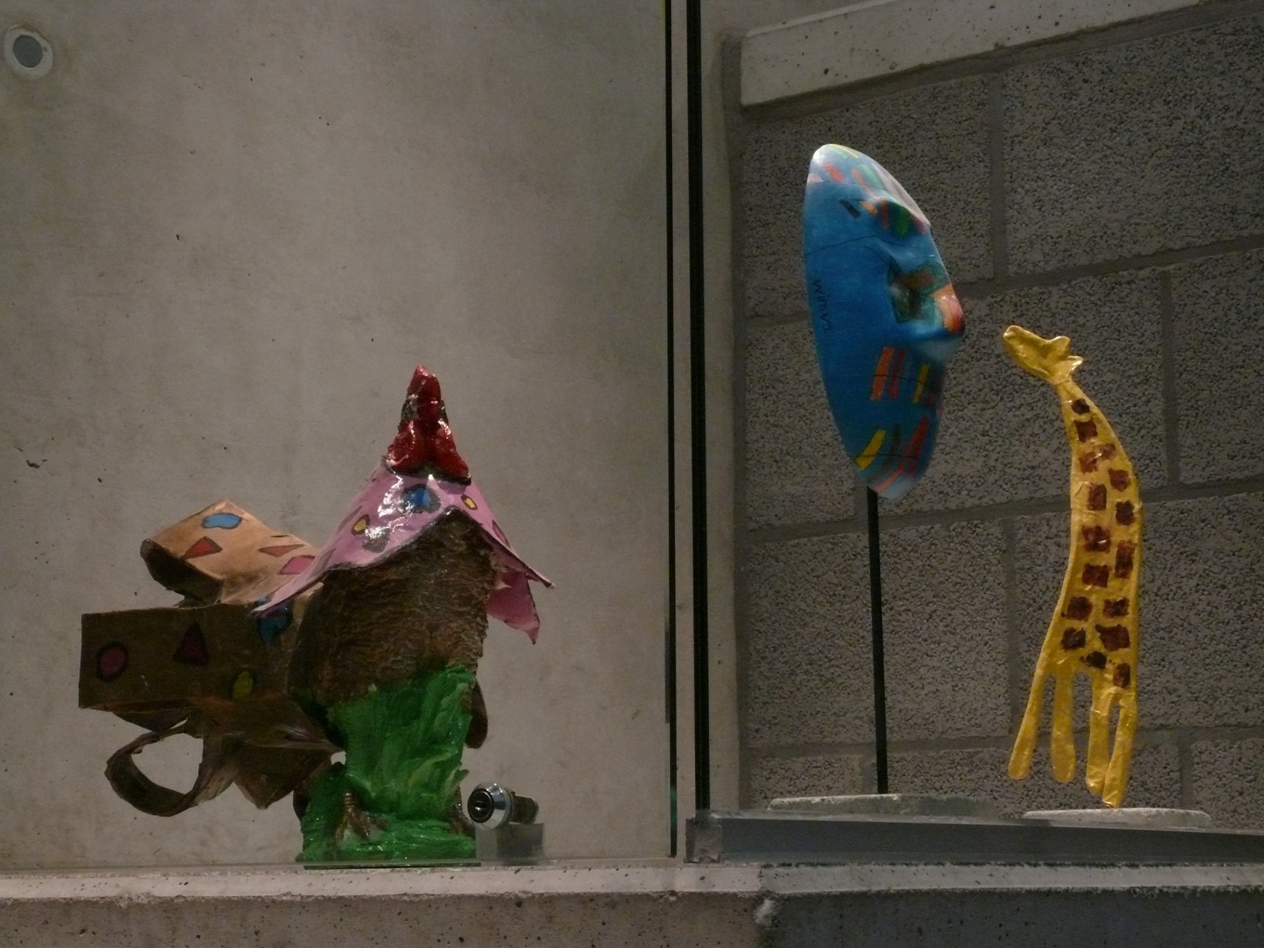 Kleurrijke sculpturen: huisje, blauw masker en gele giraf