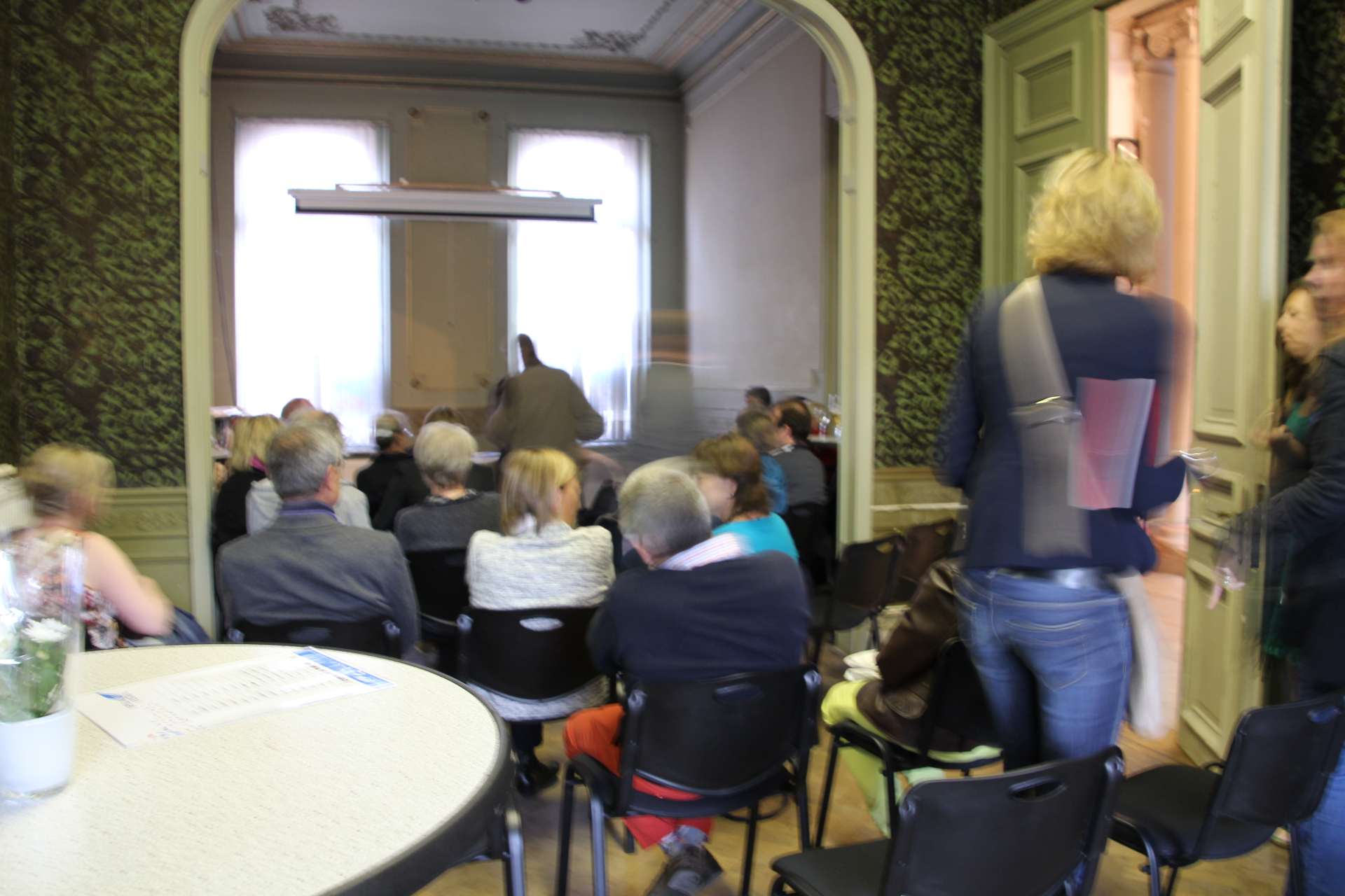 Publiek in een historische zaal tijdens een lezing