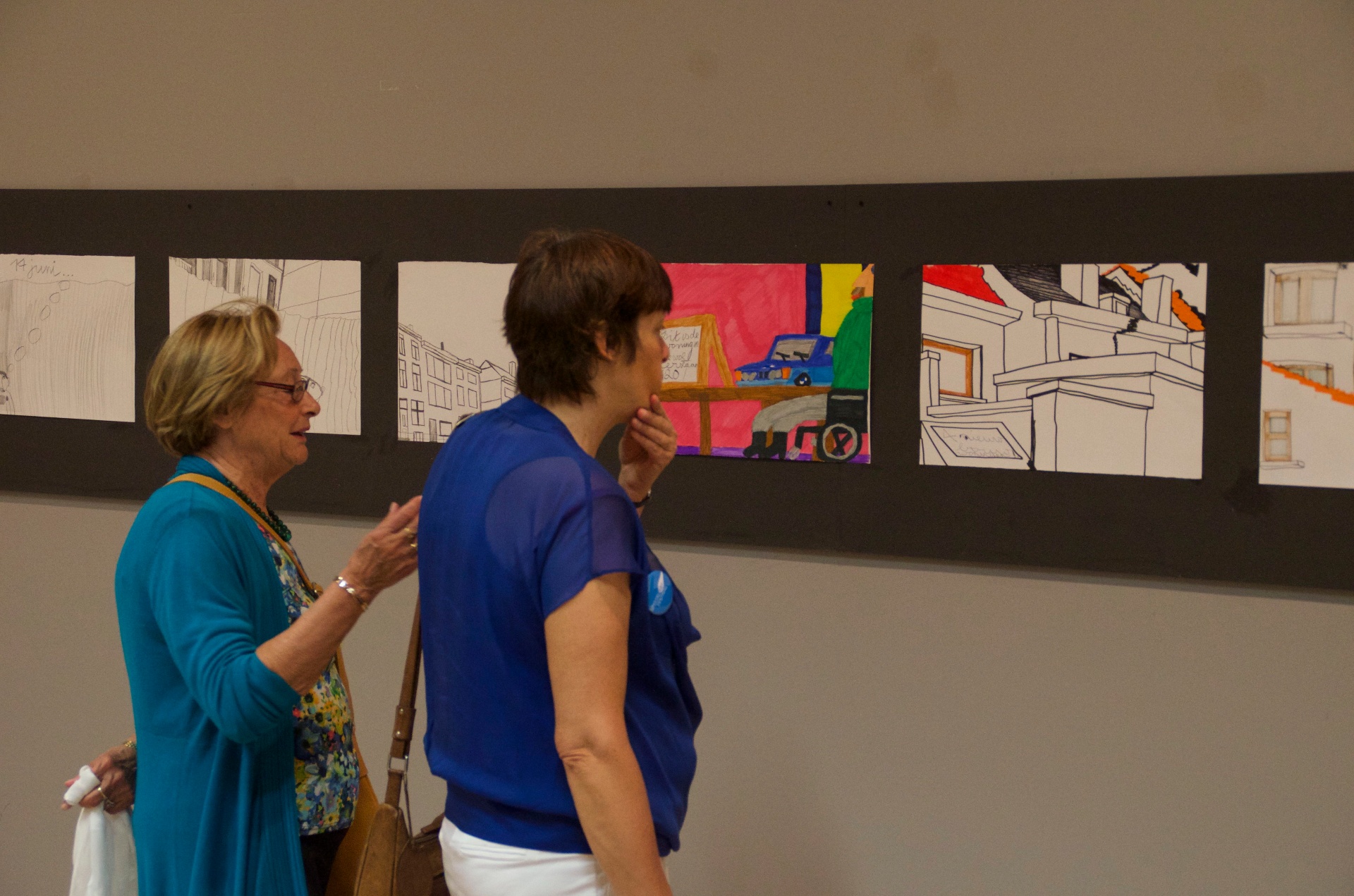 Bezoekers bij tekeningen aan de wand tijdens de expo