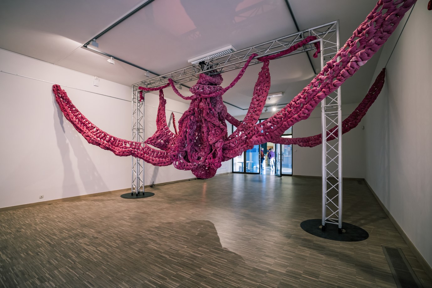 Grote roze gehaakte installatie hangend in de tentoonstellingsruimte