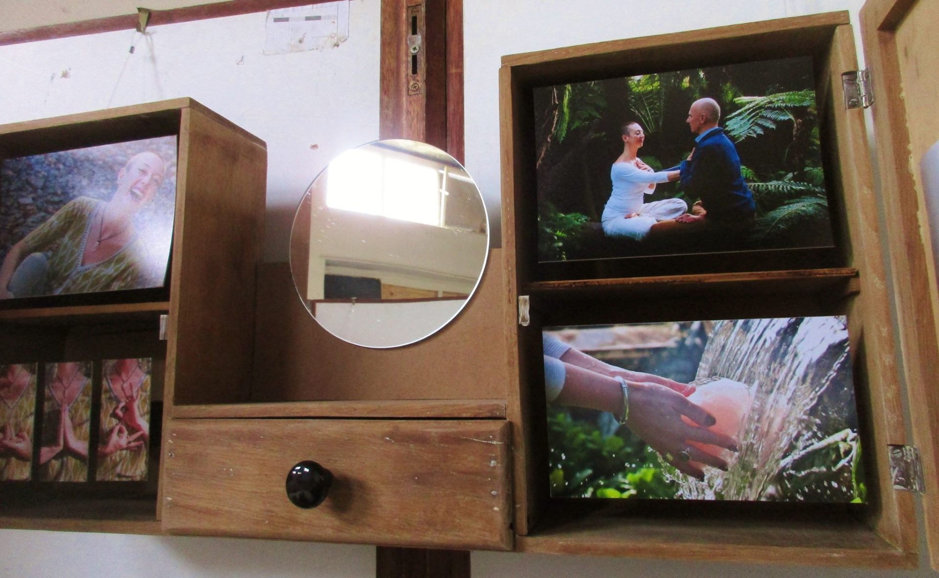 Houten kastjes met foto's, een ronde spiegel en een lade