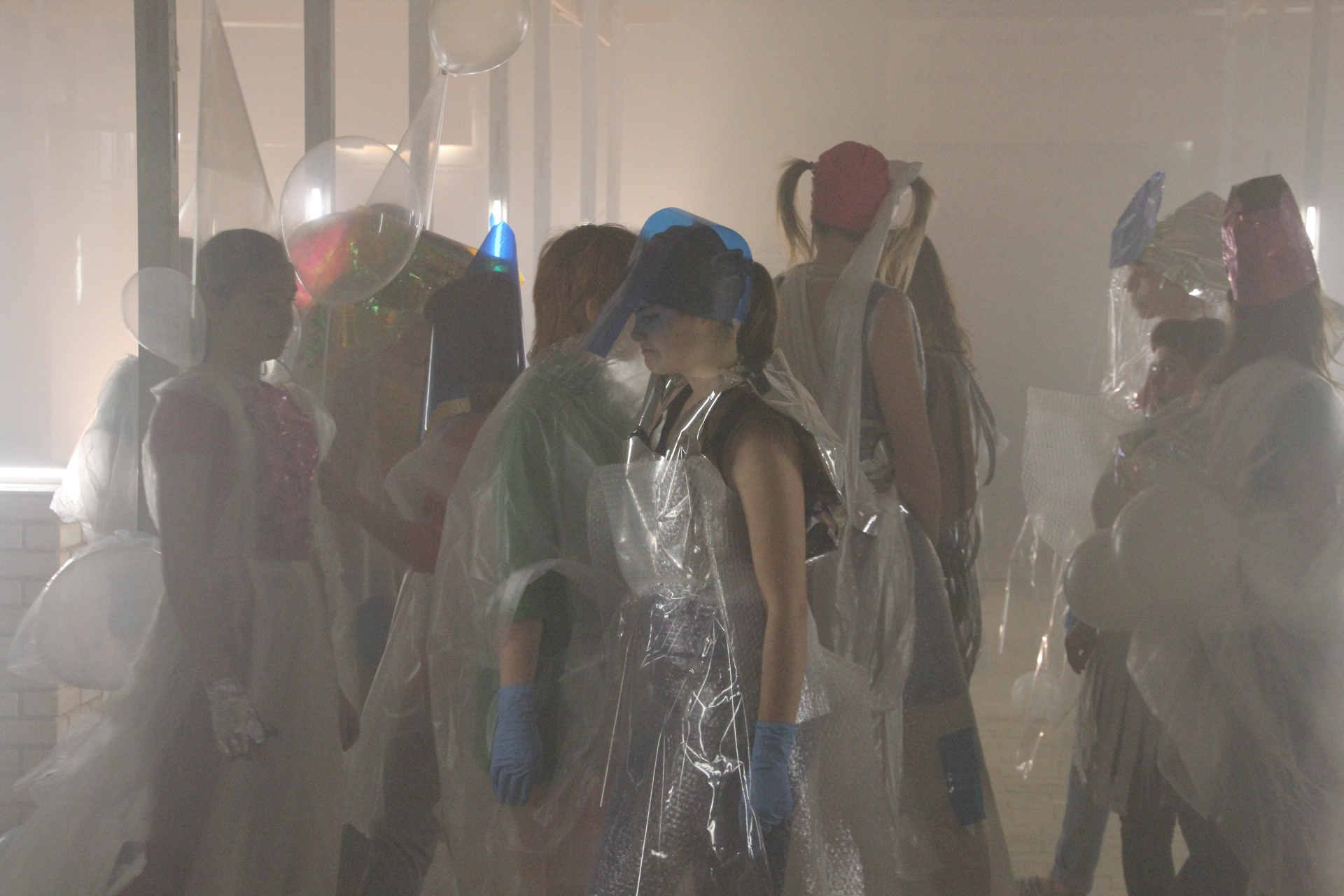 Performers in transparante kostuums in een mistige ruimte